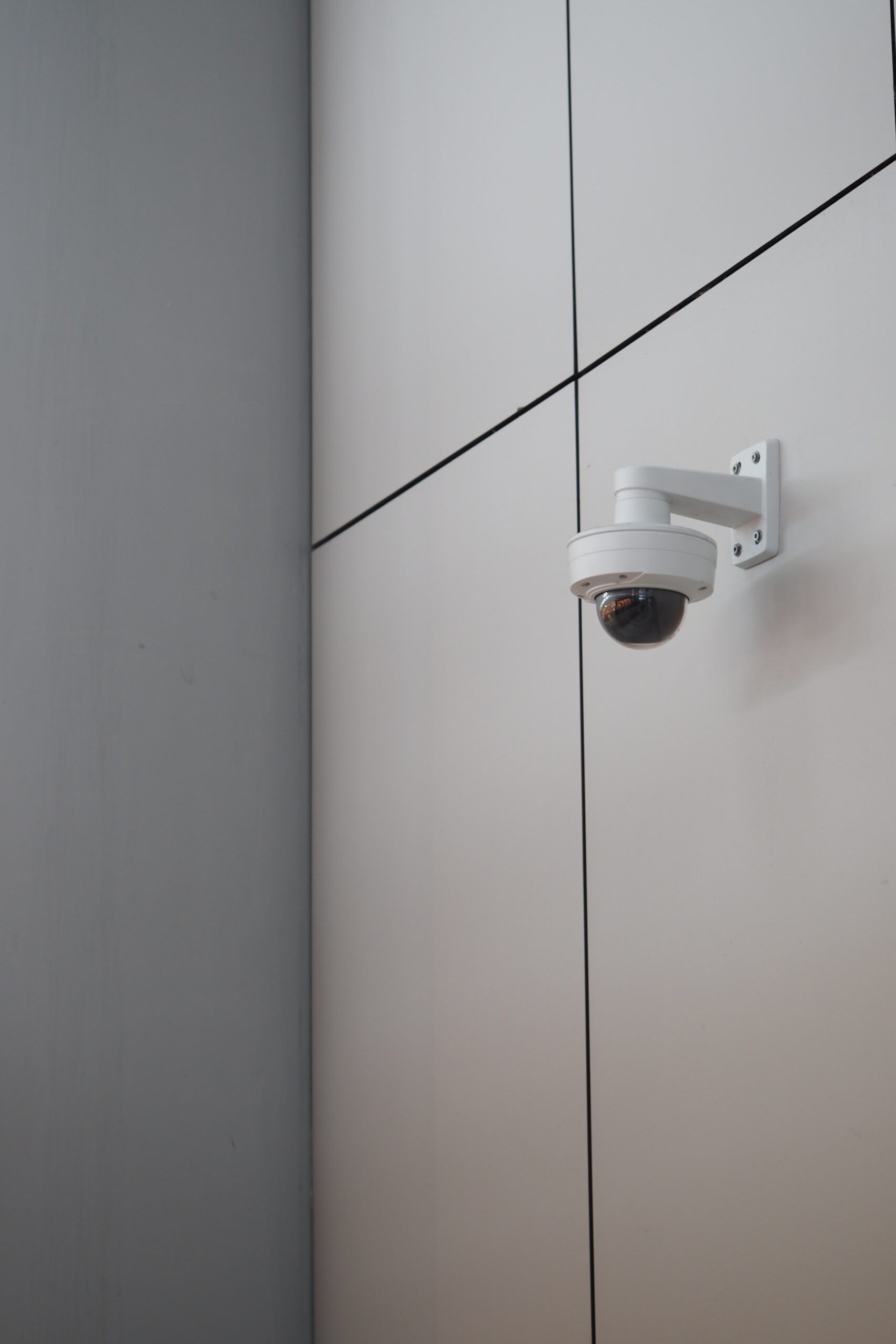 A white surveillance camera is installed high on a stylish wall.